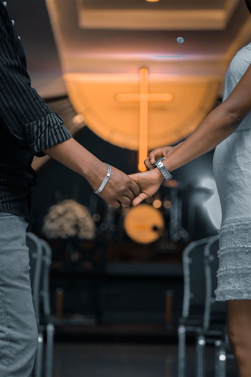 Casal de mãos dadas em frente à cruz na igreja